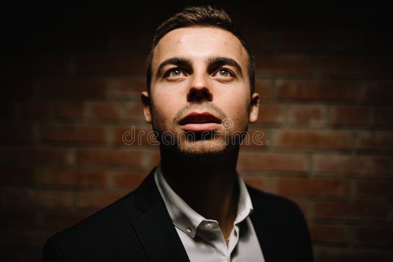 El hombre de moda en un fondo del negro lleva a cabo su mano en la cara fotos de archivo El hombre de moda en un fondo del negro lleva a cabo su mano en la cara fotos de archivo