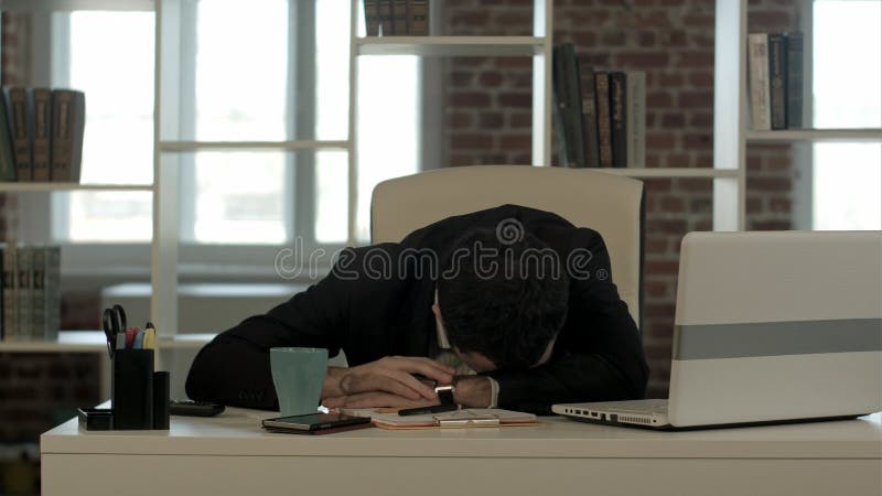 El hombre de negocios cansado que duerme con el ordenador portátil, despierta y comienza a hablar el teléfono foto de archivo libre de regalías El hombre de negocios cansado que duerme con el ordenador portátil, despierta y comienza a hablar el teléfono foto de archivo libre de regalías