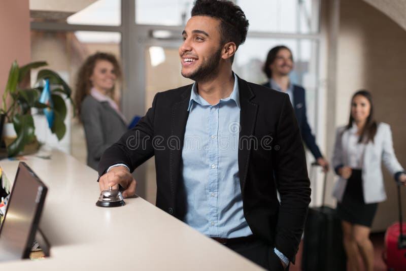 Hispanic Business Man Arrive To Hotel Waiting For Check In Registration Business People Group In Lobby, Guests Arrive. Hispanic Business Man Arrive To Hotel Waiting For Check In Registration Business People Group In Lobby, Guests Arrive