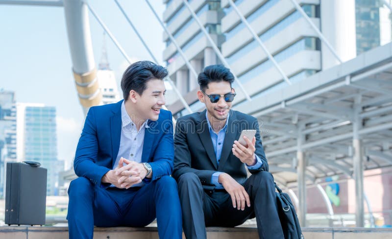 El hombre de negocios joven sonriente utiliza smartphone que disfruta de una conversación positiva que habla con un socio comerci foto de archivo El hombre de negocios joven sonriente utiliza smartphone que disfruta de una conversación positiva que habla con un socio comerci foto de archivo