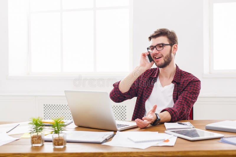 El hombre de negocios joven tiene una charla móvil en oficina blanca moderna fotografía de archivo El hombre de negocios joven tiene una charla móvil en oficina blanca moderna fotografía de archivo