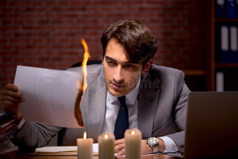 El hombre de negocios que quema las pruebas tarde en oficina imagenes de archivo