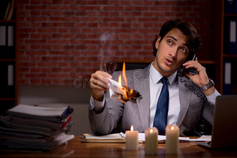 El hombre de negocios que quema las pruebas tarde en oficina foto de archivo