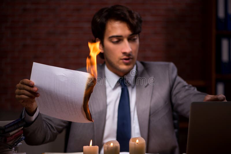 El hombre de negocios que quema las pruebas tarde en oficina foto de archivo libre de regalías