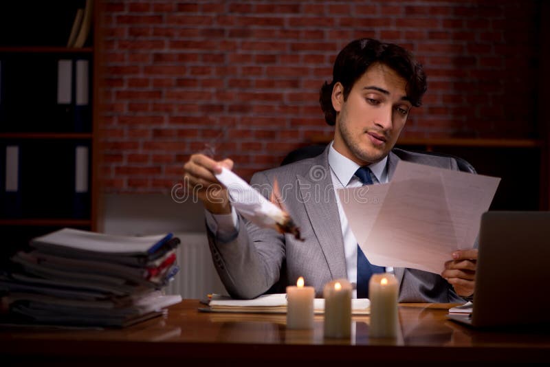 El hombre de negocios que quema las pruebas tarde en oficina fotografía de archivo libre de regalías