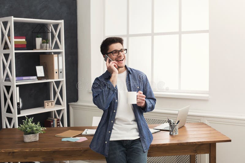 El hombre de negocios sonriente joven tiene charla móvil foto de archivo libre de regalías El hombre de negocios sonriente joven tiene charla móvil foto de archivo libre de regalías