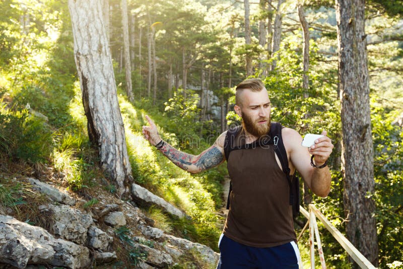 El hombre elegante barbudo del caminante que usa la navegación de los gps para colocar en el rastro de montaña y piensa adonde ir imagen de archivo El hombre elegante barbudo del caminante que usa la navegación de los gps para colocar en el rastro de montaña y piensa adonde ir imagen de archivo