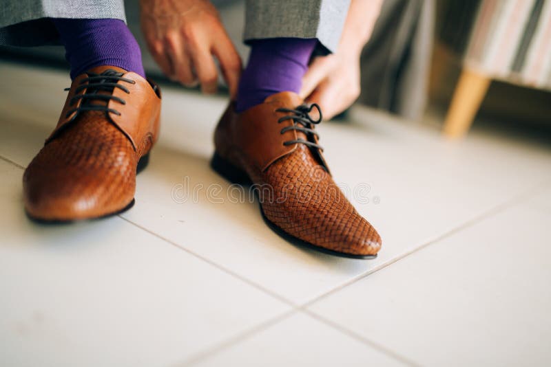 El hombre en holguras grises y un vestido púrpura pega los zapatos marrones con fotografía de archivo