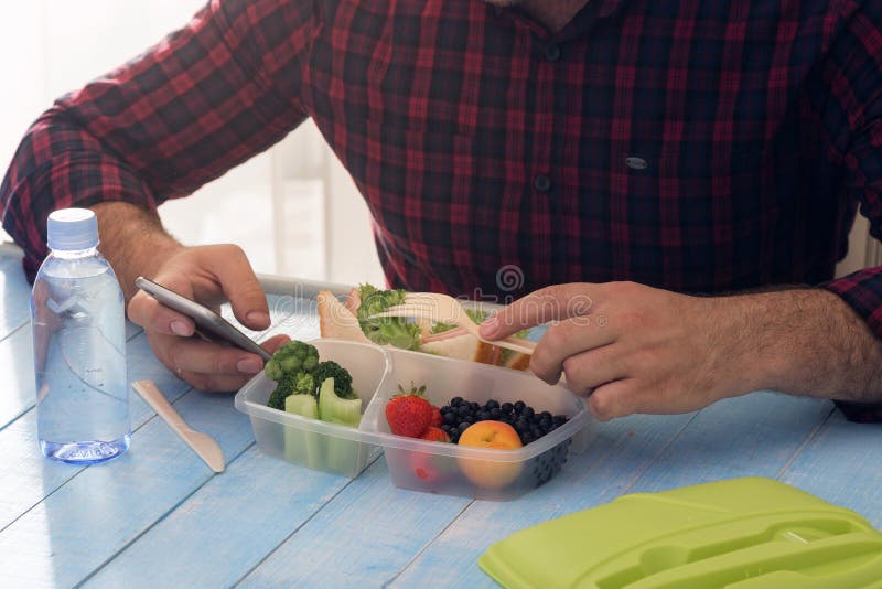 El hombre está teniendo comida sana del almuerzo que se sienta en la tabla de madera imagenes de archivo El hombre está teniendo comida sana del almuerzo que se sienta en la tabla de madera imagenes de archivo