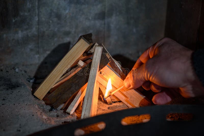 El hombre fija el fuego a la madera en el horno imagen de archivo El hombre fija el fuego a la madera en el horno imagen de archivo