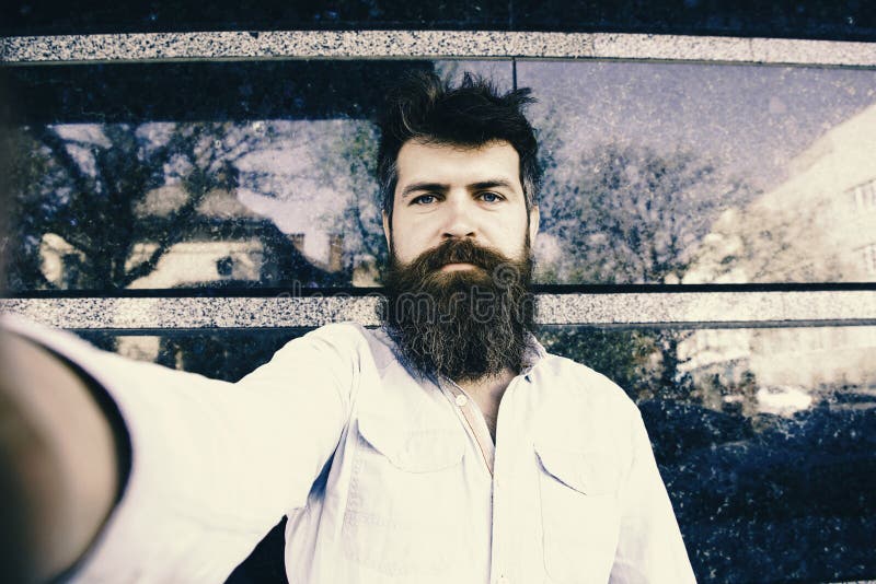 El hombre hace selfies Concepto de Vlogging Inconformista, turista con el pelo despeinado y barba larga que mira la cámara, toman fotografía de archivo El hombre hace selfies Concepto de Vlogging Inconformista, turista con el pelo despeinado y barba larga que mira la cámara, toman fotografía de archivo