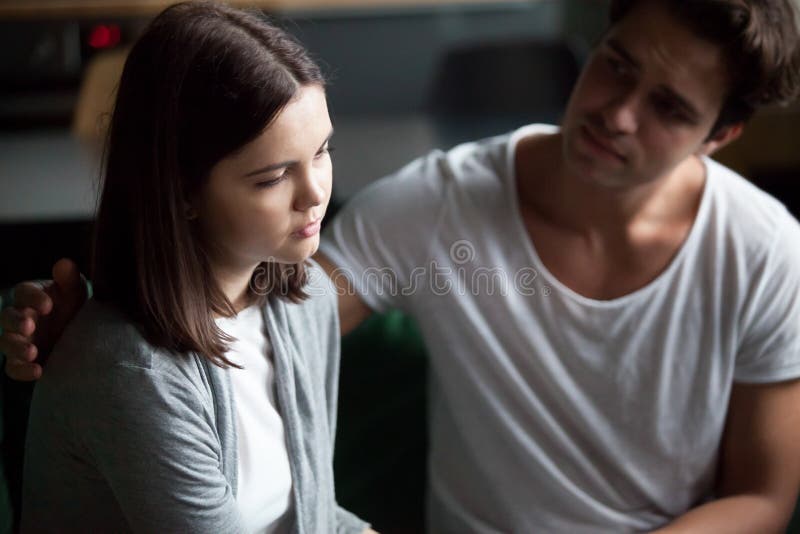 El hombre joven calma a la muchacha infeliz en casa imagenes de archivo El hombre joven calma a la muchacha infeliz en casa imagenes de archivo