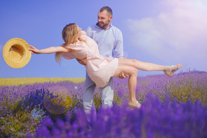 El hombre joven detiene a la mujer en el campo de la lavanda, par joven lindo en amor caminando en un campo de las flores de la l imagen de archivo El hombre joven detiene a la mujer en el campo de la lavanda, par joven lindo en amor caminando en un campo de las flores de la l imagen de archivo