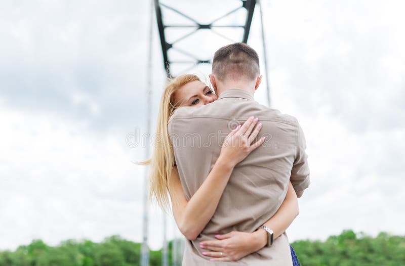 El hombre joven está abrazando con su muchacha cariñosa en el puente Visión posterior fotografía de archivo libre de regalías El hombre joven está abrazando con su muchacha cariñosa en el puente Visión posterior fotografía de archivo libre de regalías
