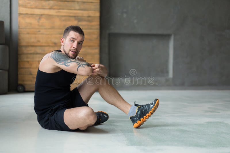 El hombre joven hermoso se relaja en el gimnasio después de entrenar foto de archivo libre de regalías El hombre joven hermoso se relaja en el gimnasio después de entrenar foto de archivo libre de regalías