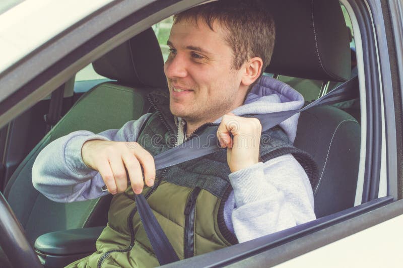 El hombre joven sujeta el cinturón de seguridad Conducción segura