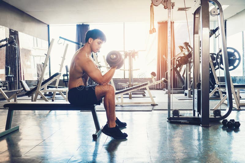 El hombre muscular construyó al atleta que se resolvía en el gimnasio que se sentaba en weightl fotografía de archivo El hombre muscular construyó al atleta que se resolvía en el gimnasio que se sentaba en weightl fotografía de archivo