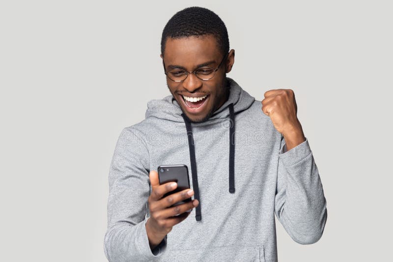 El hombre negro emocionado siente buenas noticias de la lectura extática en el teléfono móvil