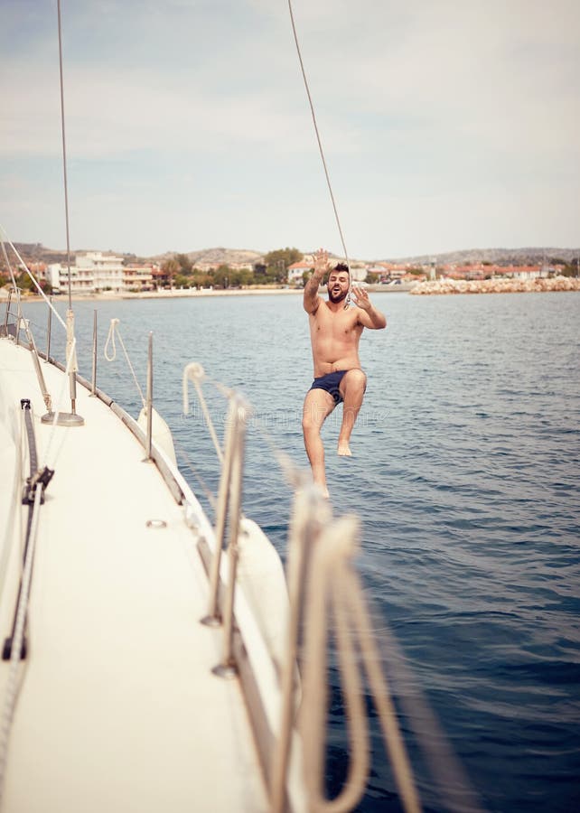 El hombre que salta del barco de navegación en el mar imágenes de archivo libres de regalías El hombre que salta del barco de navegación en el mar imágenes de archivo libres de regalías