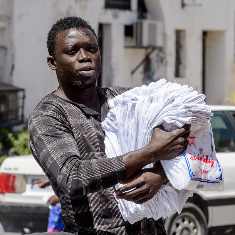 El hombre senegalés no identificado camina a lo largo de la calle con las mercancías f imagen de archivo El hombre senegalés no identificado camina a lo largo de la calle con las mercancías f imagen de archivo