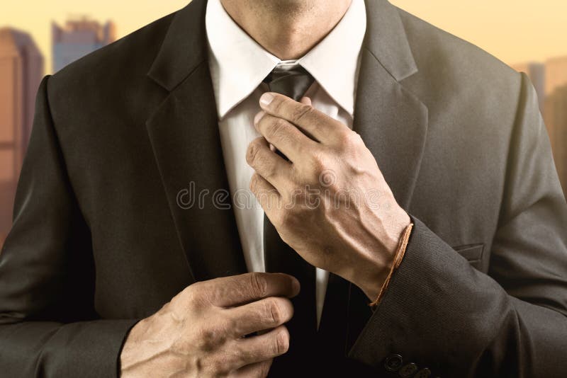 El hombre vestido en traje y la camisa blanca ajusta su lazo fotografía de archivo libre de regalías El hombre vestido en traje y la camisa blanca ajusta su lazo fotografía de archivo libre de regalías