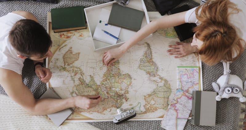 El hombre y la mujer están planeando vacaciones usando un mapa del mundo y otros accesorios del viaje