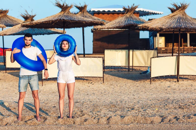 El hombre y la mujer están presentando en la playa y están llevando a cabo círculos inflables concepto de día de fiesta del mar d imagen de archivo libre de regalías El hombre y la mujer están presentando en la playa y están llevando a cabo círculos inflables concepto de día de fiesta del mar d imagen de archivo libre de regalías