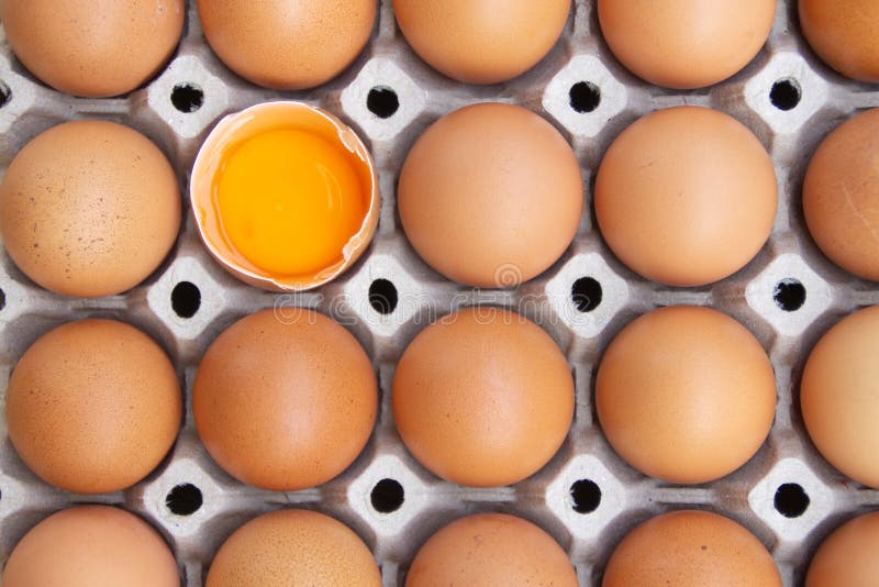 El huevo de pollo marrón se rompe a la mitad entre otros huevos, huevos envasados en cartón o cajas para transporte, huevo de pol fotografía de archivo El huevo de pollo marrón se rompe a la mitad entre otros huevos, huevos envasados en cartón o cajas para transporte, huevo de pol fotografía de archivo