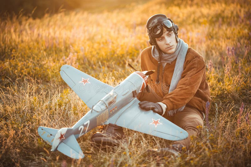 El individuo en vintage viste al piloto con un modelo del aeroplano al aire libre foto de archivo libre de regalías El individuo en vintage viste al piloto con un modelo del aeroplano al aire libre foto de archivo libre de regalías