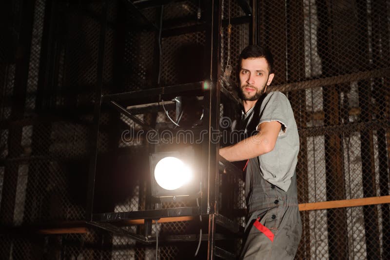 El ingeniero de iluminación ajusta las luces en etapa cerca de las escenas fotografía de archivo libre de regalías El ingeniero de iluminación ajusta las luces en etapa cerca de las escenas fotografía de archivo libre de regalías
