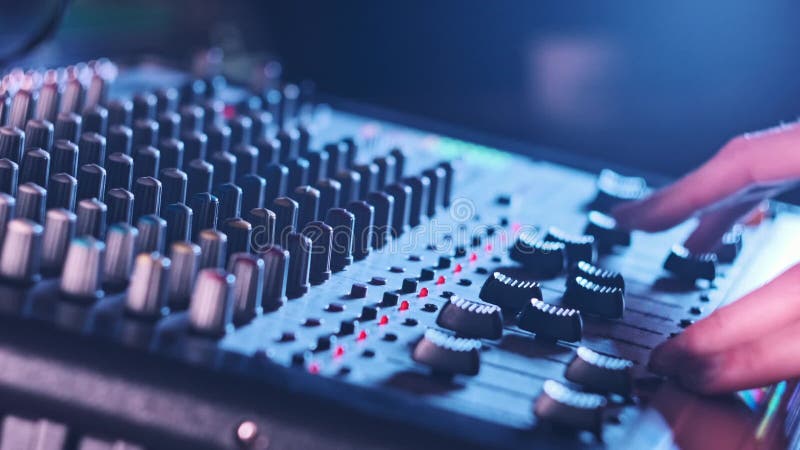 El ingeniero de sonido se desplaza hacia arriba y hacia abajo en el mezclador de audio en el cierre de la luz de neón metrajes