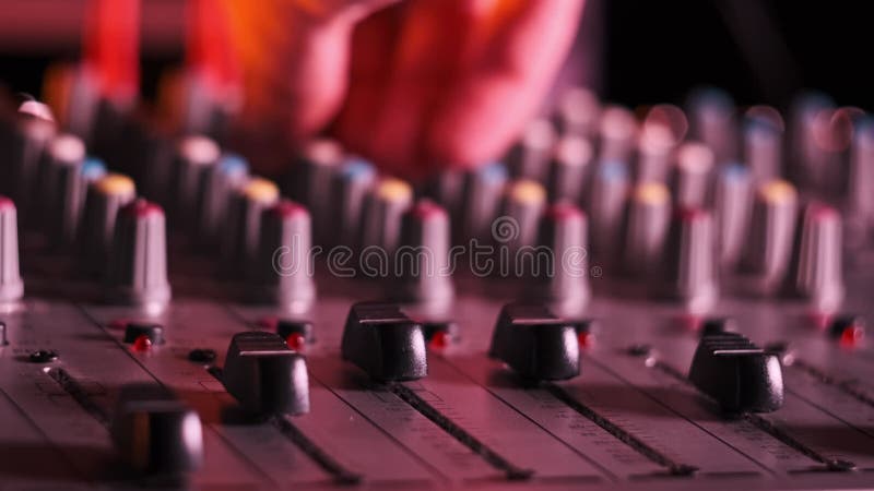 El ingeniero de sonido se desplaza hacia arriba y hacia abajo en el mezclador de audio en el cierre de la luz de neón metrajes