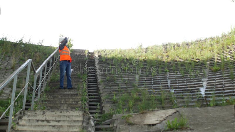 El ingeniero del inspector desciende las escaleras y examina el lugar para la construcción, va abajo de las escaleras