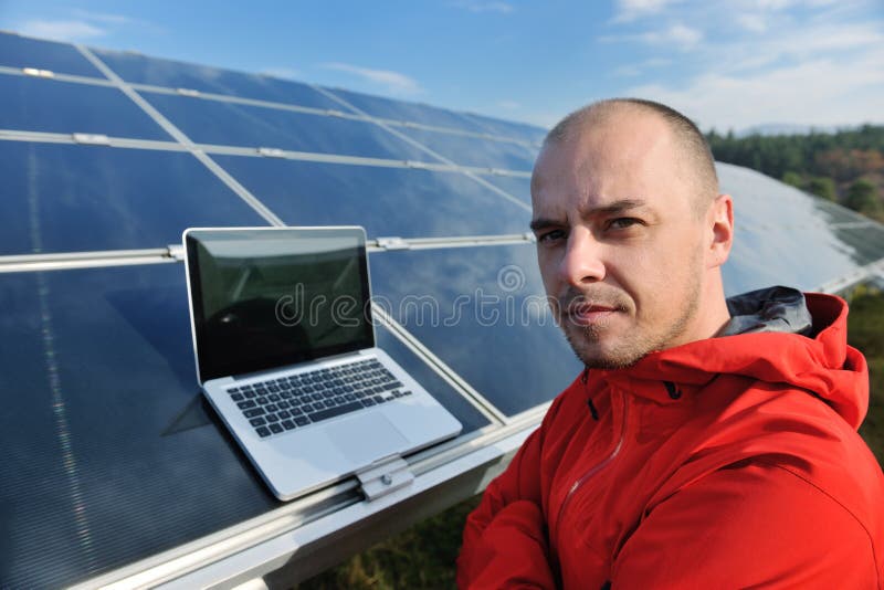 El ingeniero que usa la computadora portátil en los paneles solares planta el campo imagen de archivo libre de regalías El ingeniero que usa la computadora portátil en los paneles solares planta el campo imagen de archivo libre de regalías