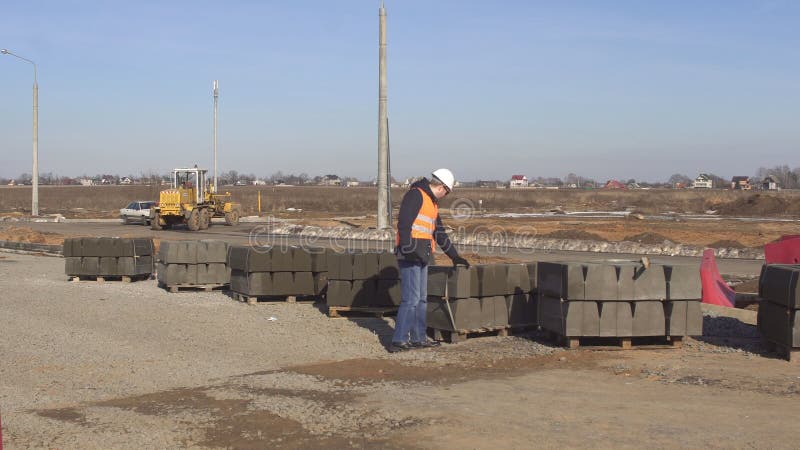 El inspector del inspector comprueba la calidad del encintado del camino durante la construcción del camino, ingeniero