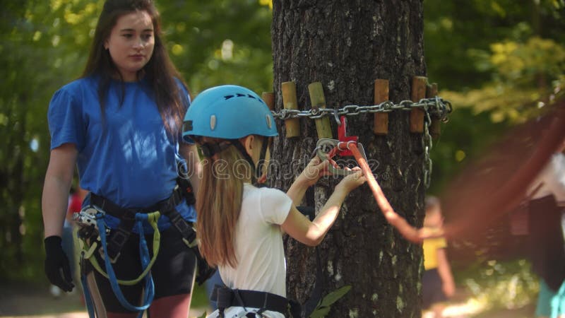 El inspector le explica a la niña cómo atarse un gancho protector a la cuerda - una aventura extrema en el