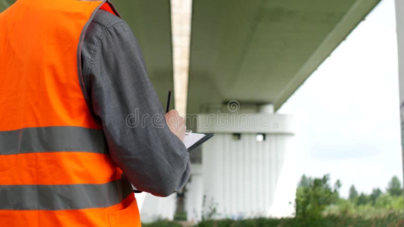 El inspector registra las violaciones encontradas durante la inspección del puente a través del río, primer, examinador y