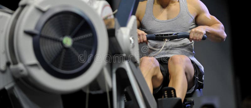 El instructor muscular atractivo potente de CrossFit del hombre hace entrenamiento en remero interior en el gimnasio foto de archivo libre de regalías El instructor muscular atractivo potente de CrossFit del hombre hace entrenamiento en remero interior en el gimnasio foto de archivo libre de regalías