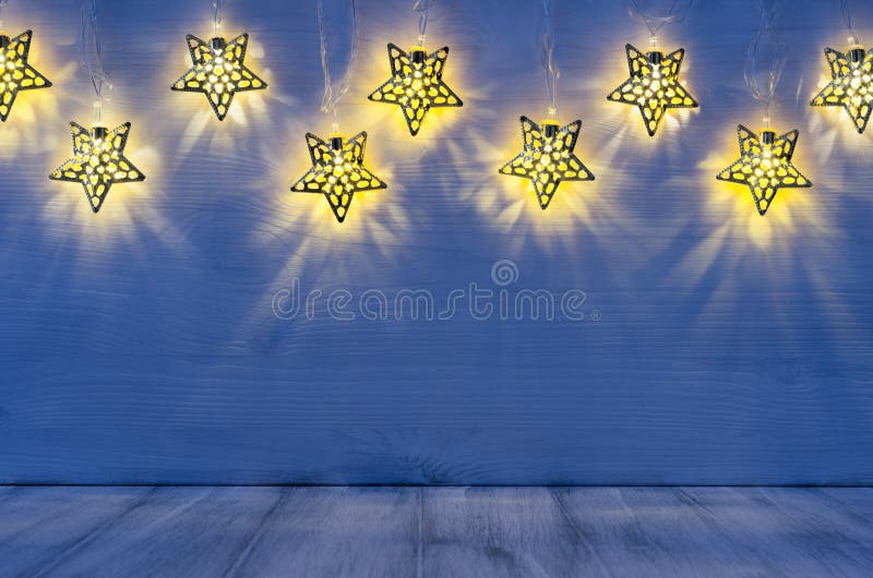 El interior en blanco de la Navidad con resplandor enciende las estrellas amarillas en fondo de madera de los azules añiles foto de archivo libre de regalías El interior en blanco de la Navidad con resplandor enciende las estrellas amarillas en fondo de madera de los azules añiles foto de archivo libre de regalías