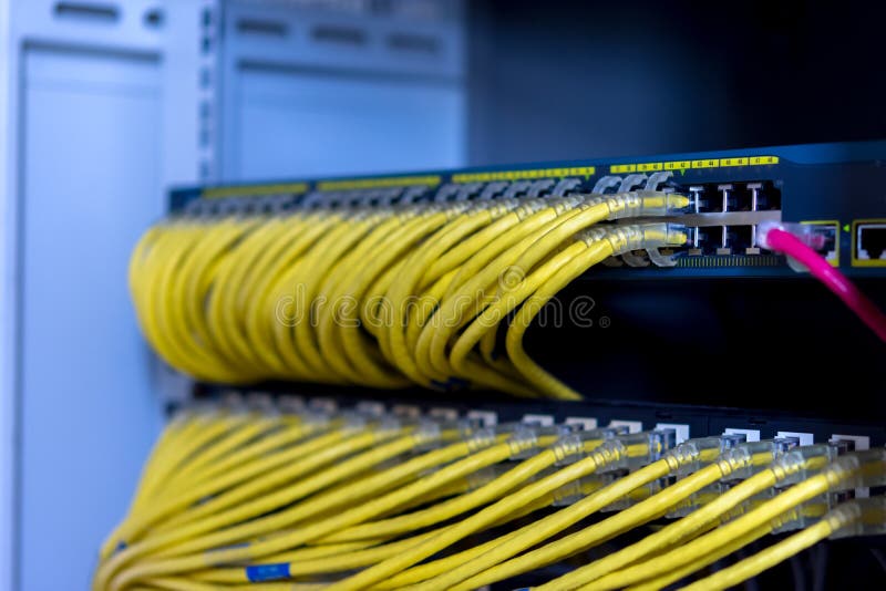 El interruptor de red en el gabinete del estante con los cables amarillos del cordón de remiendo del utp conectó fotos de archivo libres de regalías El interruptor de red en el gabinete del estante con los cables amarillos del cordón de remiendo del utp conectó fotos de archivo libres de regalías