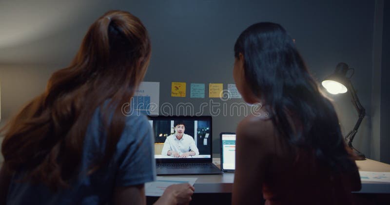 El joven estudiante asia señoras viendo clases en línea y estudiando con el sitio del compañero de habitación en la mesa en la sal almacen de metraje de vídeo