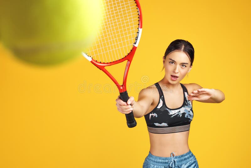 El jugador de tenis deportivo hermoso de la mujer joven tiró la bola con la estafa roja sobre fondo amarillo fotografía de archivo El jugador de tenis deportivo hermoso de la mujer joven tiró la bola con la estafa roja sobre fondo amarillo fotografía de archivo