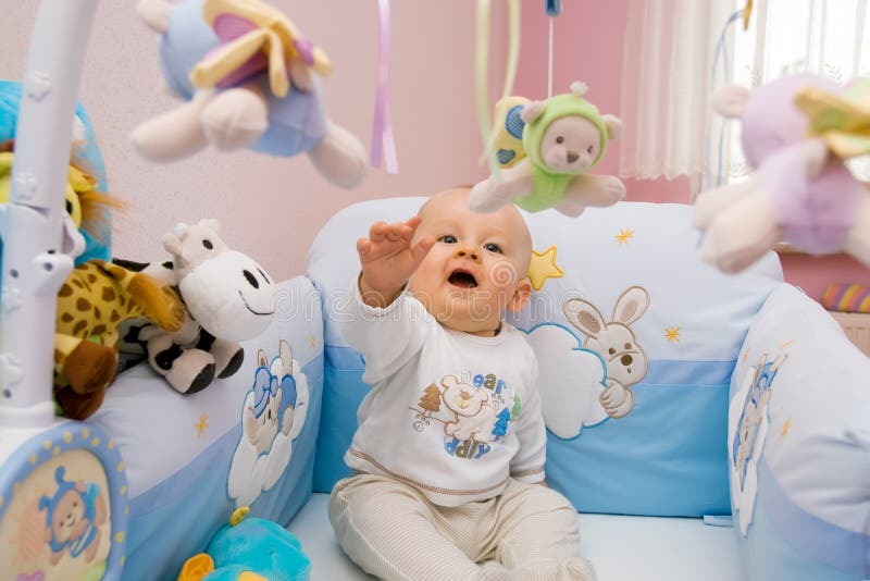 Six month baby playing with toys in bed. Baby tries to catch flying toy. Six month baby playing with toys in bed. Baby tries to catch flying toy.