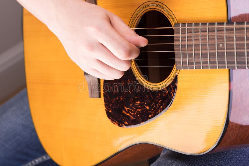 El jugar en el primer de la guitarra acústica Mano masculina para desplumar el stri fotografía de archivo El jugar en el primer de la guitarra acústica Mano masculina para desplumar el stri fotografía de archivo