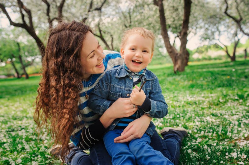El jugar feliz del hijo de la madre y del niño al aire libre en parque de la primavera o del verano fotografía de archivo El jugar feliz del hijo de la madre y del niño al aire libre en parque de la primavera o del verano fotografía de archivo