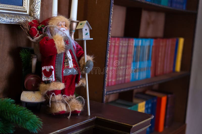 El juguete Santa Claus de la Navidad está en el estante en la biblioteca Bokeh del estante del fondo Interior del ` s del Año Nue fotos de archivo libres de regalías El juguete Santa Claus de la Navidad está en el estante en la biblioteca Bokeh del estante del fondo Interior del ` s del Año Nue fotos de archivo libres de regalías
