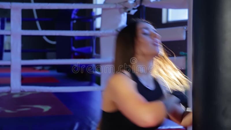 El kickboxer de la muchacha resuelve soplos en la pera en el gimnasio