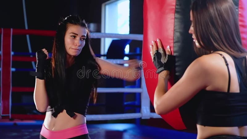 El kickboxer de la muchacha resuelve soplos en la pera en el gimnasio