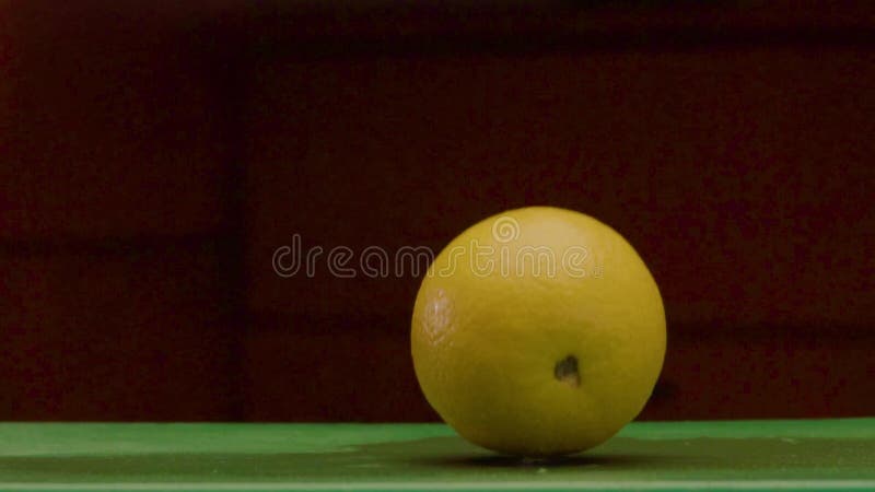 El limón amarillo redondo cae en una superficie verde húmeda