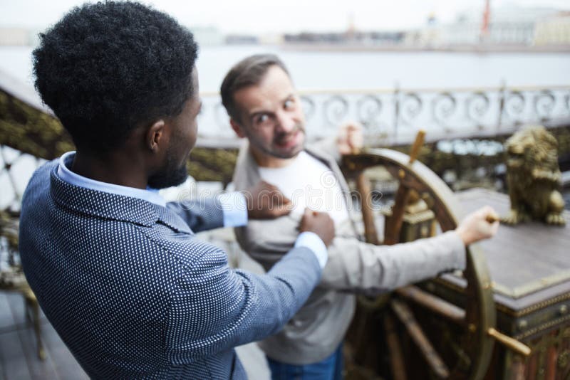 El luchar para la rueda. Dos líderes empresariales interculturales jovenes que luchan para navegar la rueda en la nave durante el movimiento